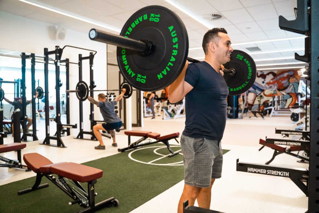 Man lifting weights in gym at Synkro Perth