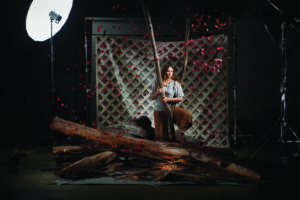 Black Swan 2023 a First Nations lady sits in a photography studio that is dimly lit.