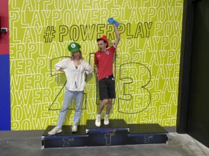 Two competitors stand on a podium. One has his arm raised in the air celebrating a win